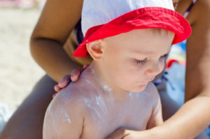 Mother applying sun screen lotion on her child???‚¬?„?s body